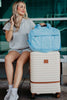 A woman traveling with a quilted blue weekender bag next to a piece of luggage