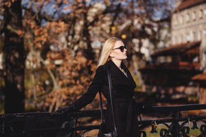 Woman in black coat standing in front of autumn trees