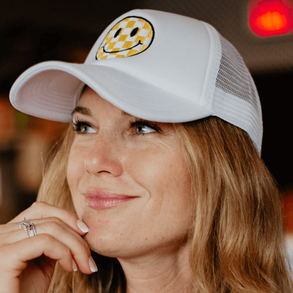 Woman wearing a checkered happy face hat bar patch on her foam trucker hat