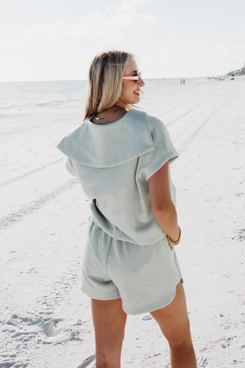 A woman walking on the beach wearing a collared mint scuba set