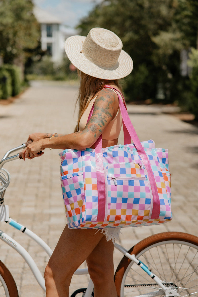 Woman on a bicycle holding a pink and blue checkered bag