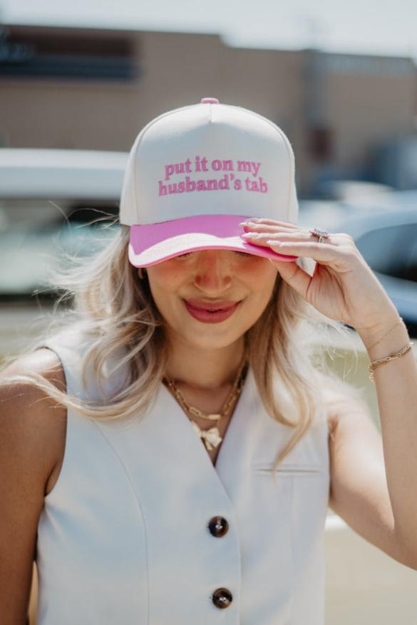 A woman wearing a trendy hat that says put it on my husband's tab