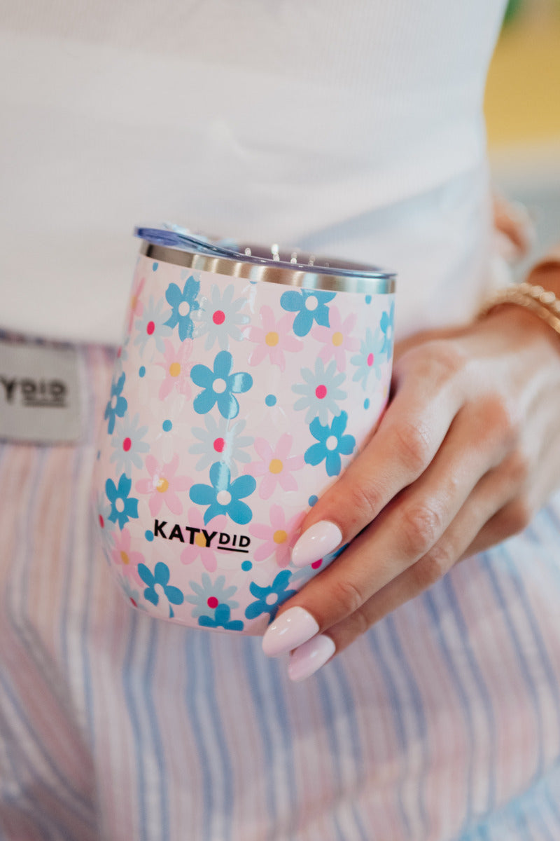 A woman holding a pink and blue floral wine tumbler