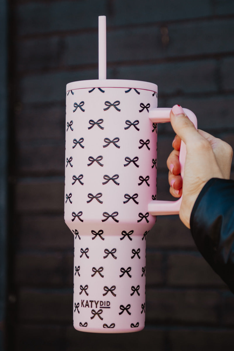 Woman holding a pink & black coquette bow tumbler