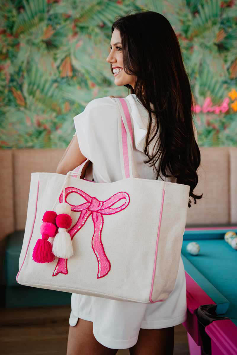 A woman holding a white tote with a pink bow design