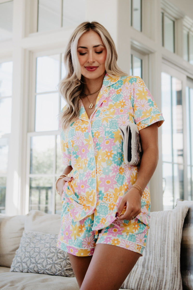 A woman standing on a couch wearing a colorful floral loungewear set